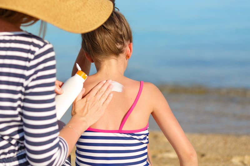 Mom applying the best sunblock for kids on her daughter's back