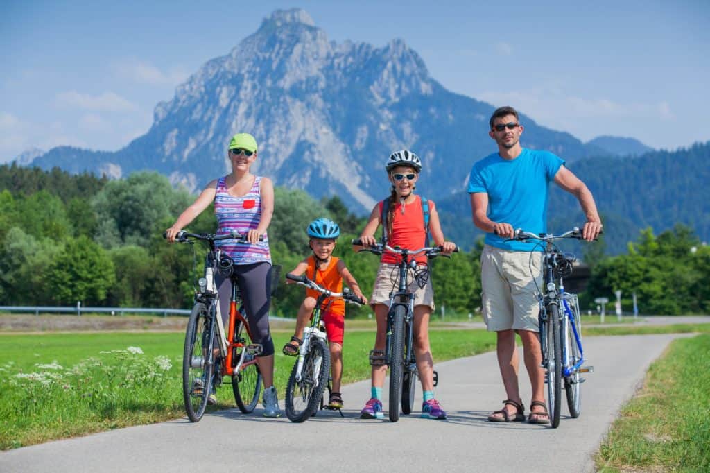 Family taking a bike ride together with picturesque mountains in the background. Discover 4 simple strategies for how to end sibling rivalry for good. And for more parenting tips and family inspiration, follow Made In A Pinch on Pinterest!