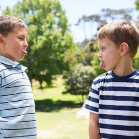 Two brothers engaged in a sticking out their tongue war. Discover our tips for how to end sibling rivalry for good. And for more parenting tips and kid inspiration, follow Made In A Pinch on Pinterest!