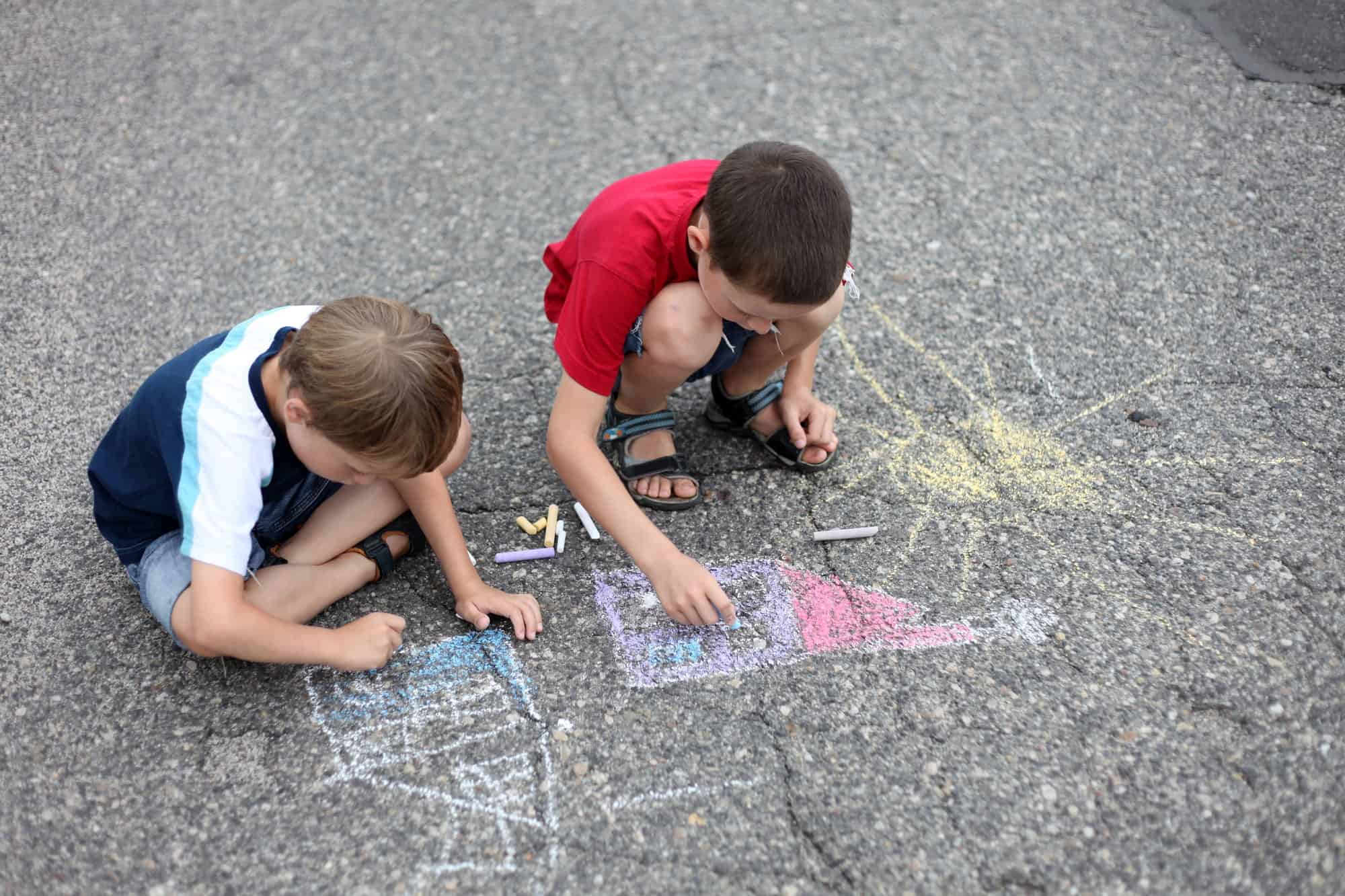 Siblings creating a sidewalk chalk masterpiece together. Discover 4 simple strategies to end sibling rivalry for good. And for more parenting tips and family inspiration, follow Made In A Pinch on Pinterest!