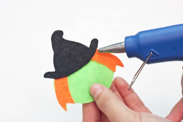 Witch Halloween bookmarks craft for kids tutorial, gluing the hat on top of the witch's head