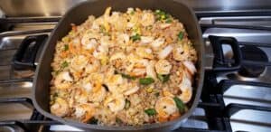 Healthy Shrimp Fried Rice with mixed vegetables, cooking a skillet on a gas range.