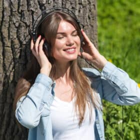 Woman sitting and enjoying music or an audiobook is a great idea for self care gifts for moms