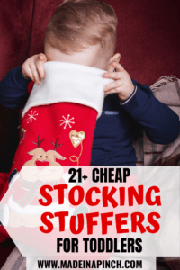 Toddler boy looking into his Christmas stocking for one of the top toddler stocking fillers ideas on this list Pinterest pin