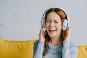 woman sitting on a couch listening to headphones and laughing