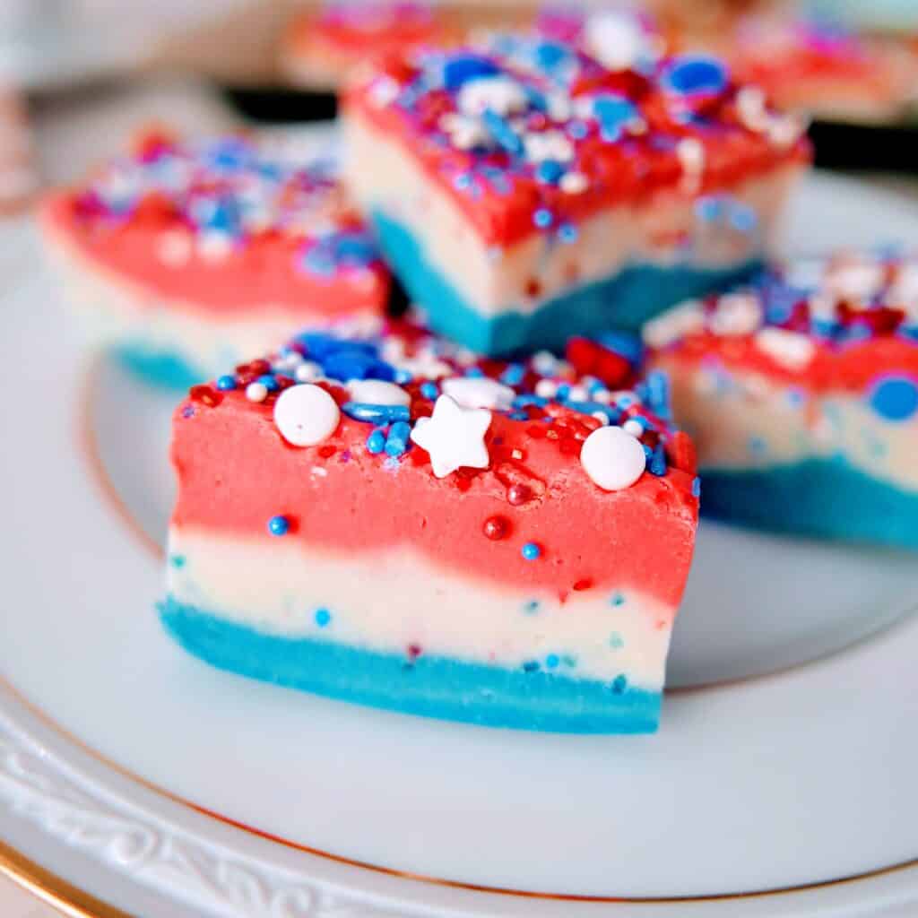 Patriotic red, white, & blue vanilla fudge recipe pieces stacked on a plate
