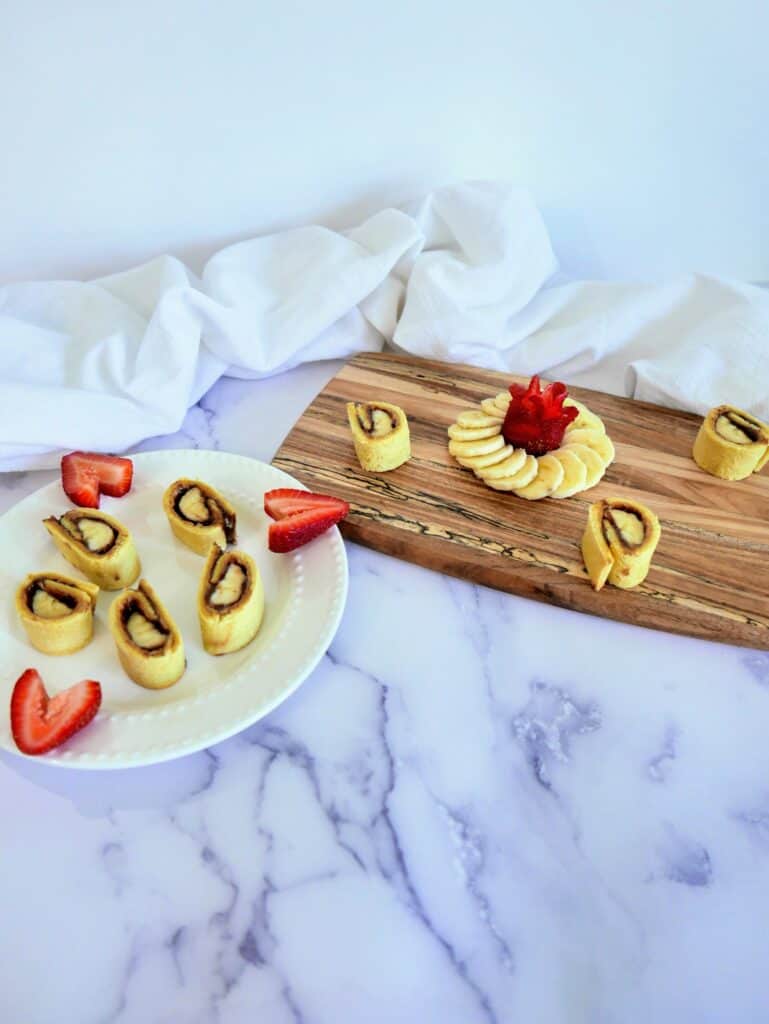 banana & peanut butter sushi rolls on a plate and wooden board