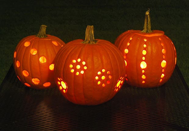 pumpkin decorating ideas for kids includes drilling patterns of holes into pumpkins like these and lighting them up