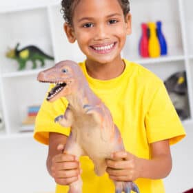 happy toddler playing with dinosaur toys