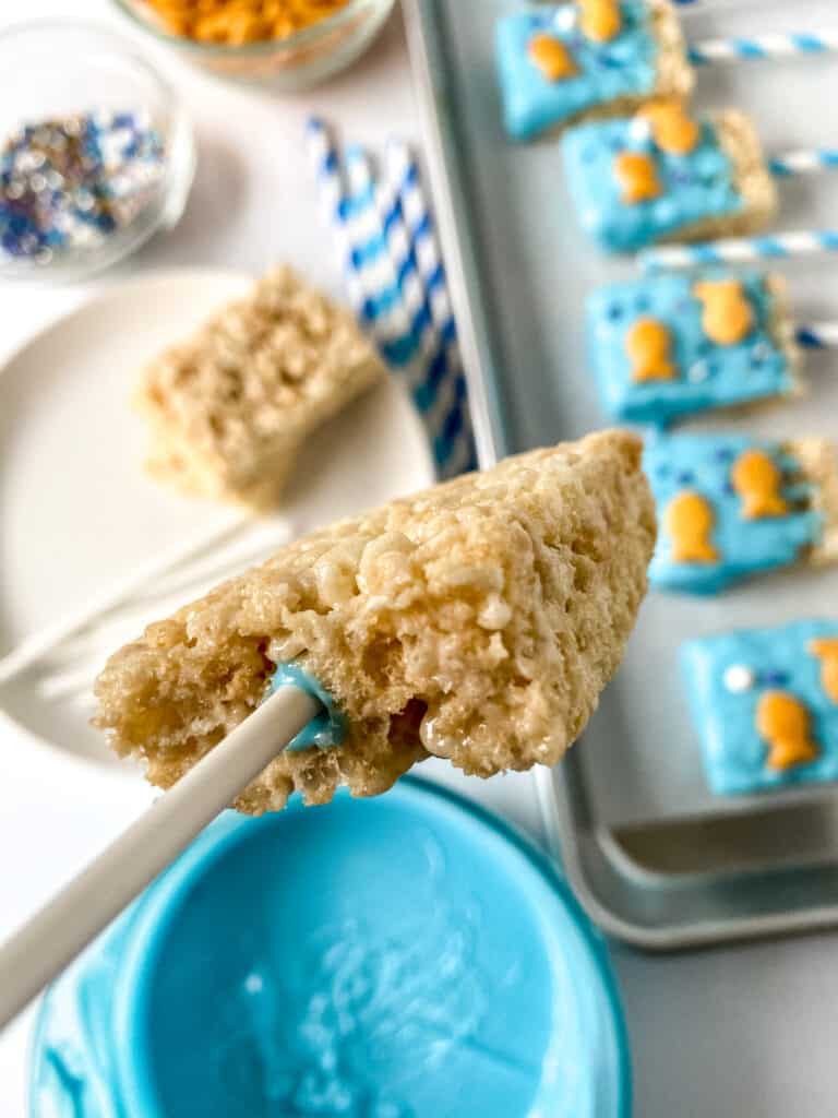 poking a paper straw into a rice krispy treat to make 1fish2fish snacks.