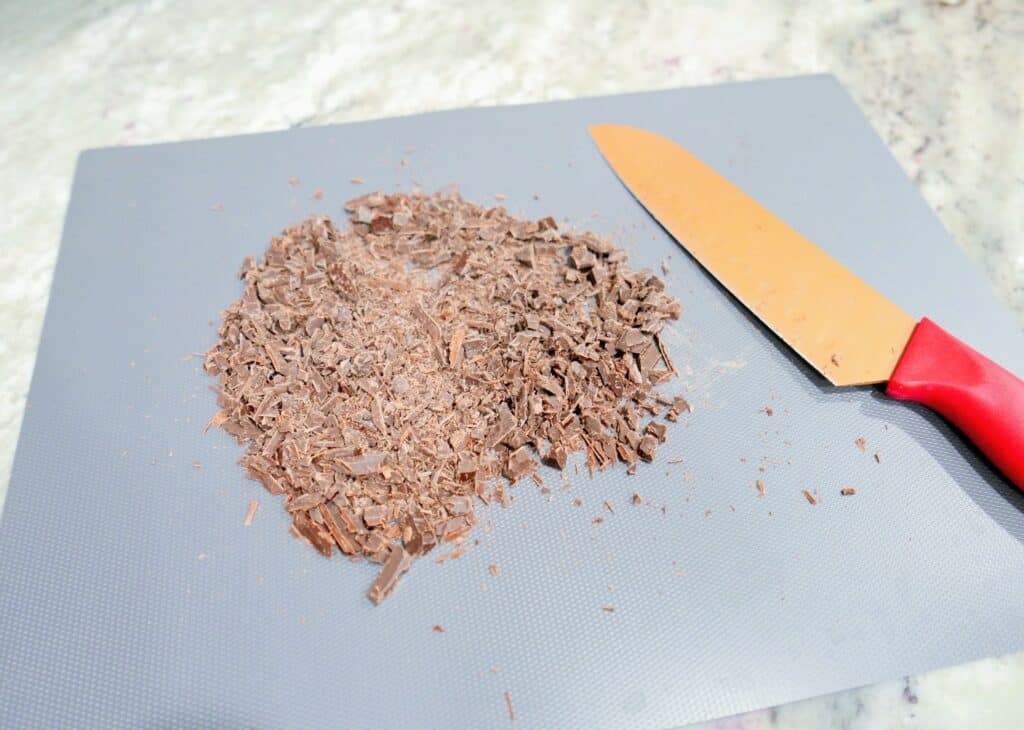 chopped chocolate bar on a tray with a knife