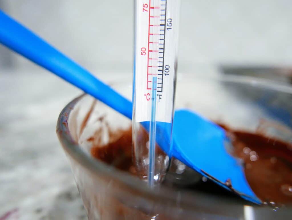 melted chocolate in a bowl with a candy thermometer showing 90 degrees
