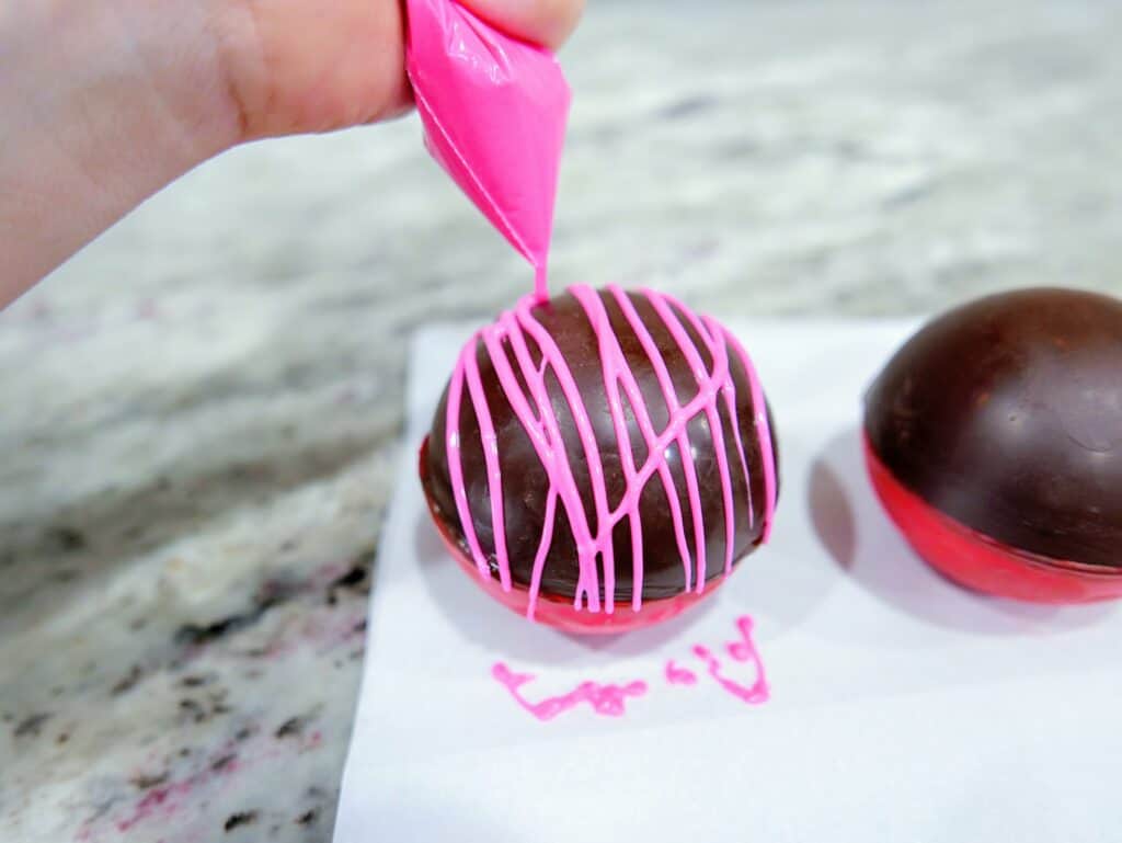 drizzling hot pink candy melts over hot cocoa bombs
