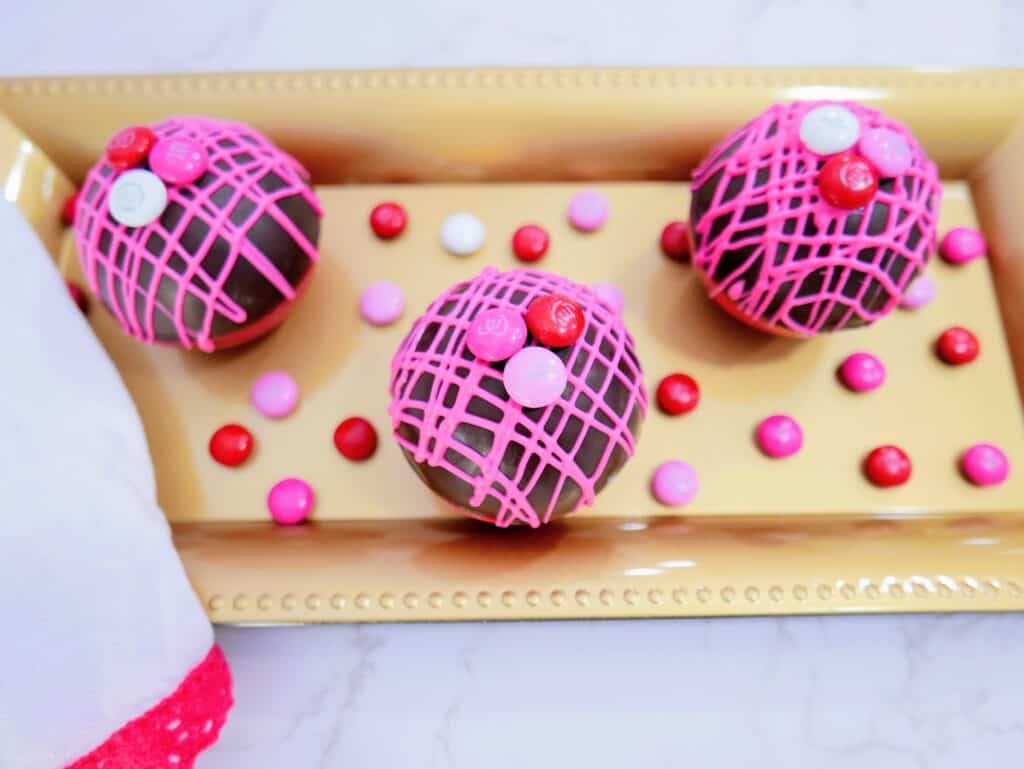 Valentine's M&M hot cocoa bombs on a gold tray