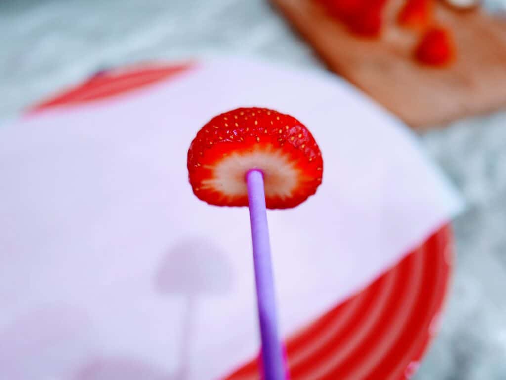 insert a lollipop stick into the top of the strawberry so you can dip it into the chocolate