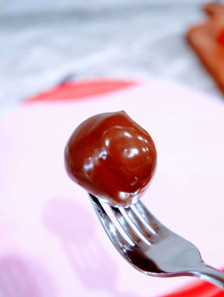 using a fork to remove chocolate-dipped strawberry from the stick