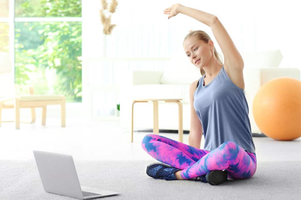 woman stretching while following one of many online fitness challenge ideas