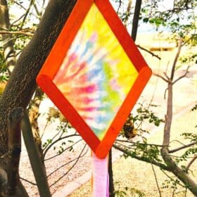 tie dye kite popsicle craft for kids hanging in a tree