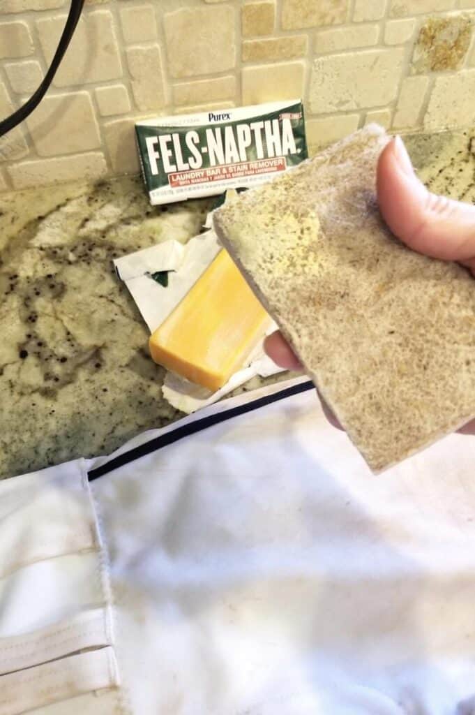 getting soap on a sponge to scrub a pair of baseball pants