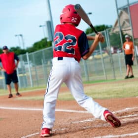 boy hitting baseball in game