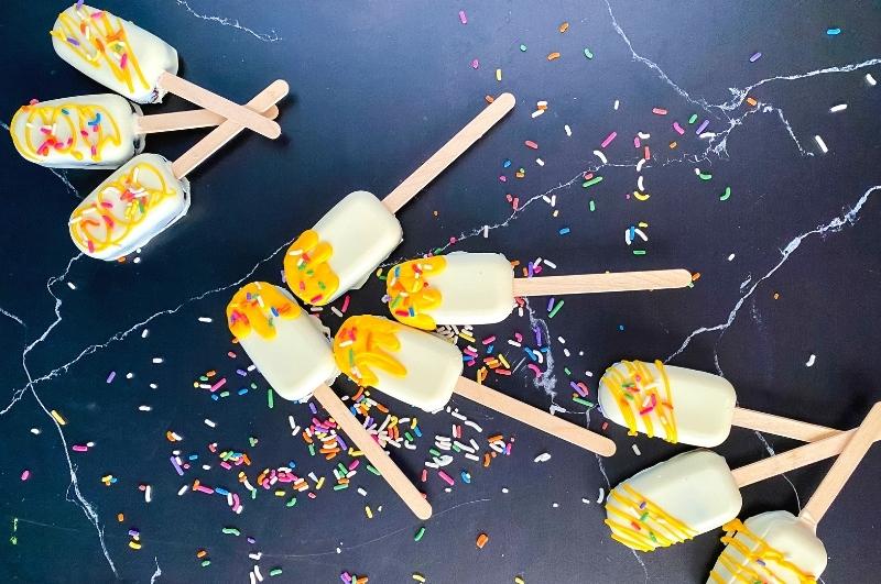 three groups of cakesicles decorated 3 different ways with icing and sprinkles