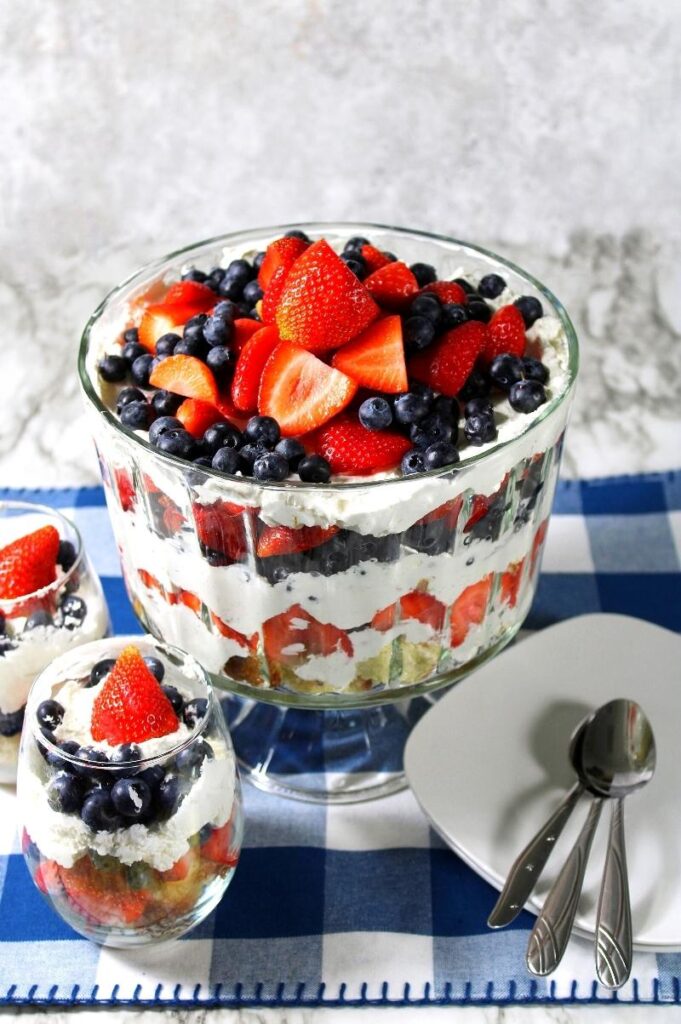 red, white, and blue trifle in large bowl with mini cups of trifle