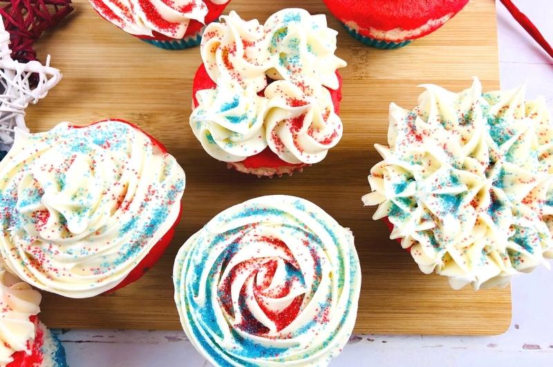 red, white, and blue cupcakes on a wood tray