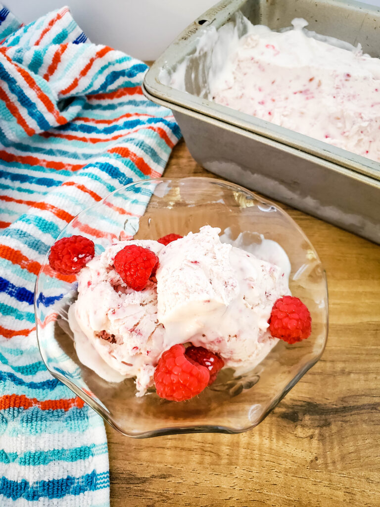 homemade no churn raspberry ice cream in a dish with fresh raspberries