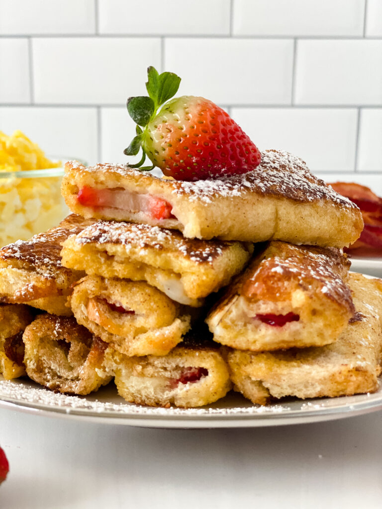Strawberry stuffed French toast piled on a plate.