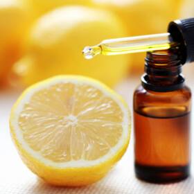 cut open lemon with bottle of essential oil