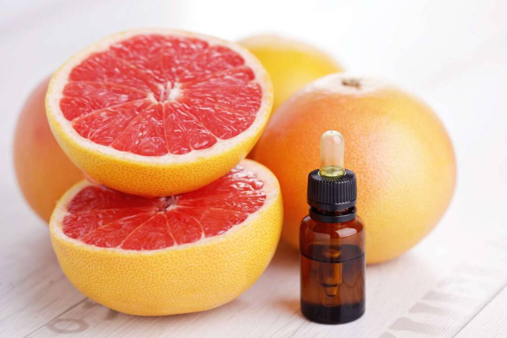 cut open grapefruit with bottle of essential oil