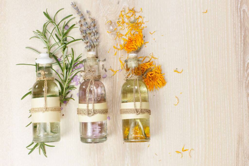 glass bottles of essential oils with sprigs of plants
