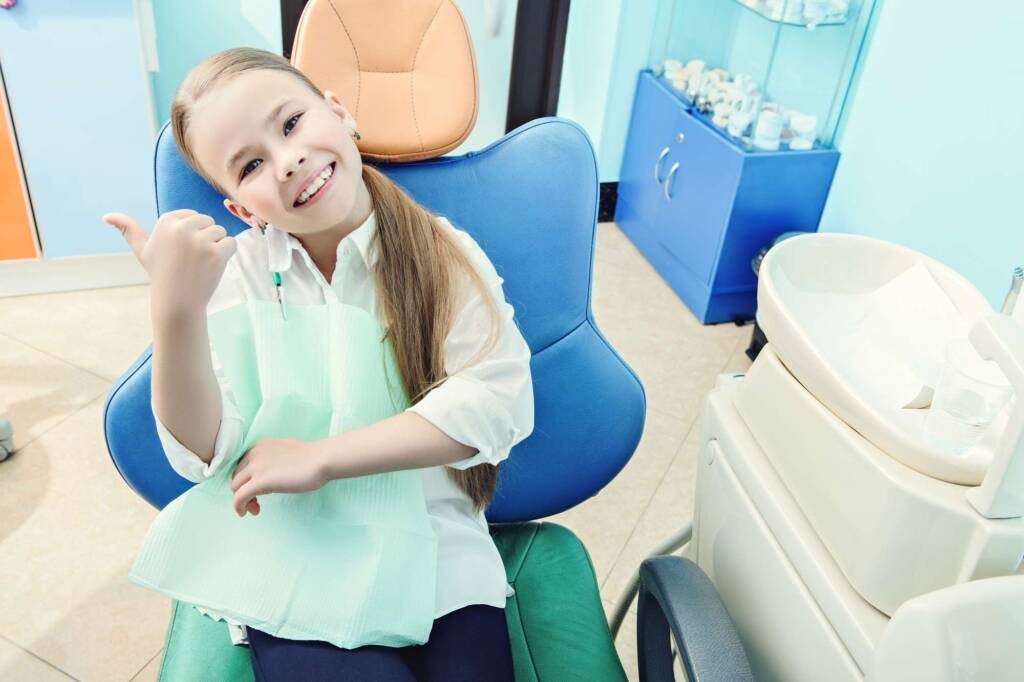 girl in dentist chair giving thumbs up