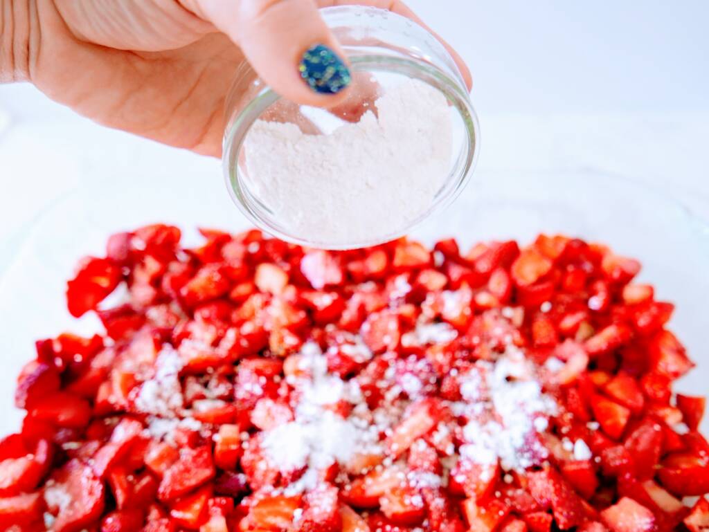 pouring flour sugar mixture on strawberries