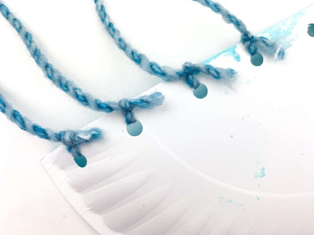 tying yarn strings to paper plate