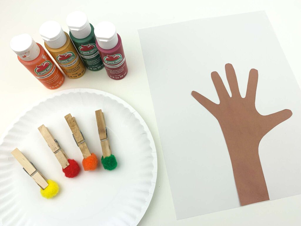 handprint glued to paper next to paint supplies