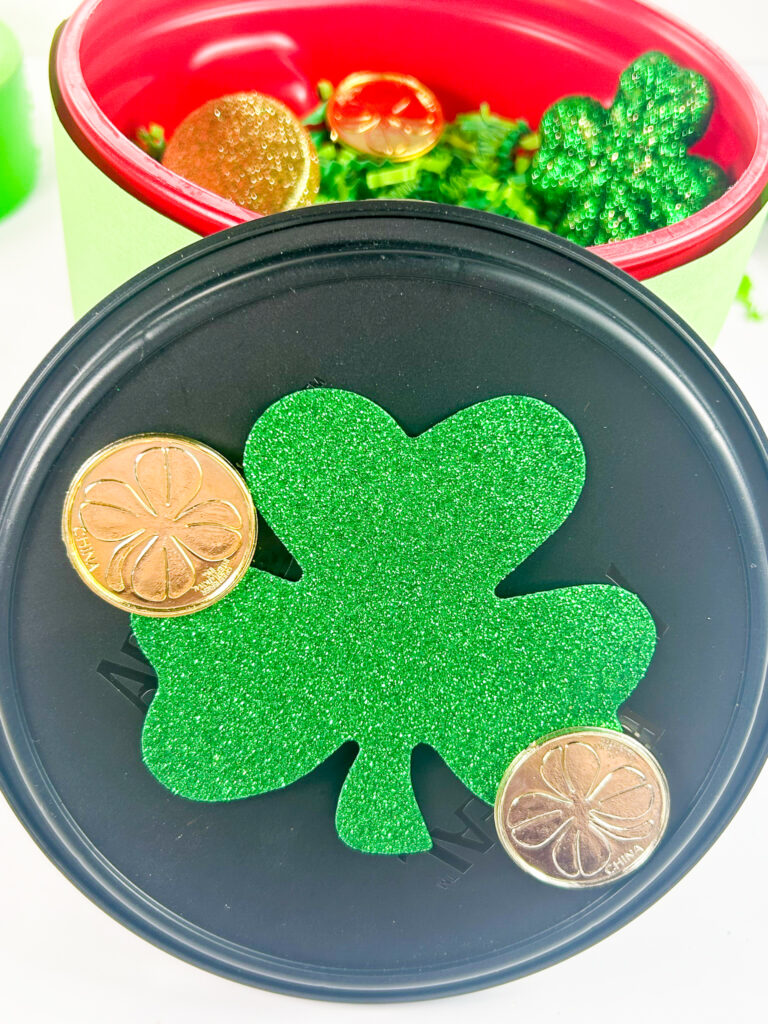 adding shamrock and gold coins to lid of coffee container