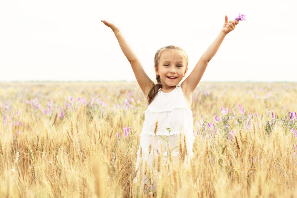 Girl in field with arms stretched out in victory