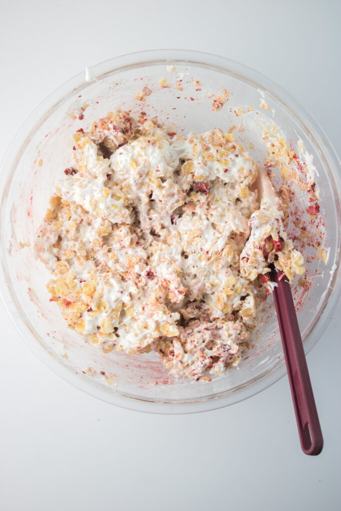 recipe process - adding melted marshmallows to rice krispies and freeze-dried strawberries