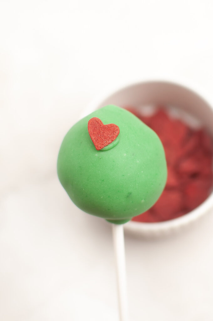 adding red heart to Grinch cake pop