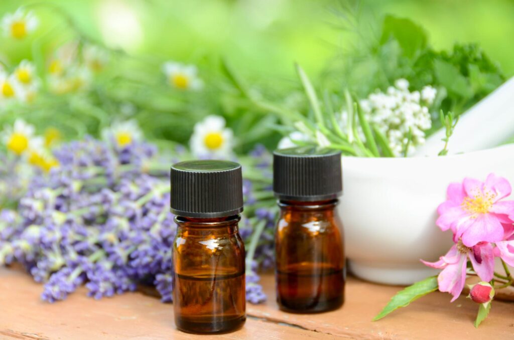 Two bottles of essential oils in front of flower blossoms