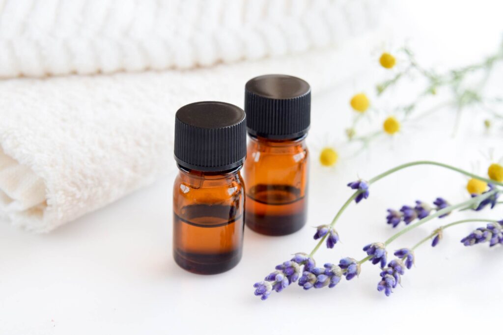 two brown bottles of essential oil on a white background with flower blossoms